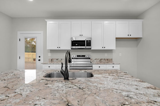 kitchen with light stone countertops, sink, white cabinetry, and stainless steel appliances