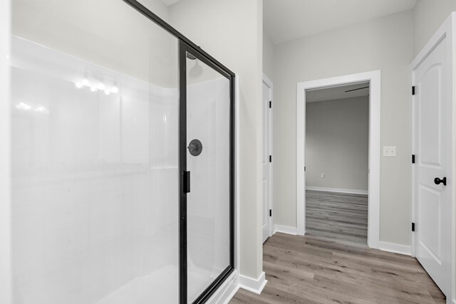 bathroom featuring a shower with shower door and wood-type flooring