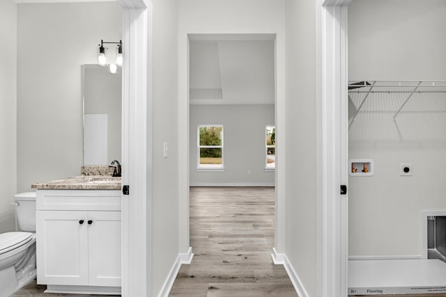 laundry room with sink, hookup for a washing machine, light hardwood / wood-style floors, and hookup for an electric dryer