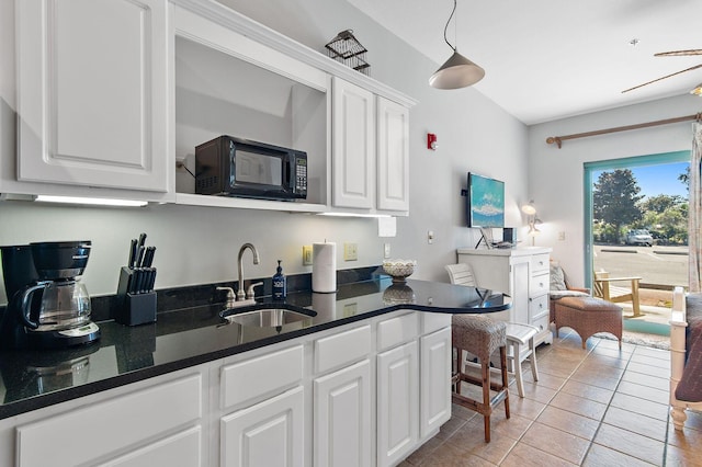 kitchen with sink, white cabinets, dark stone countertops, and light tile patterned floors