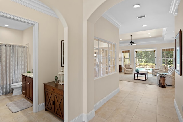 corridor with ornamental molding and light tile patterned flooring