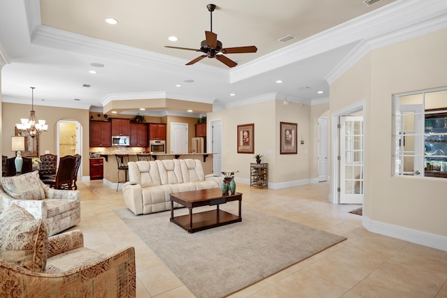 living room featuring a raised ceiling, ornamental molding, light tile patterned floors, and ceiling fan with notable chandelier