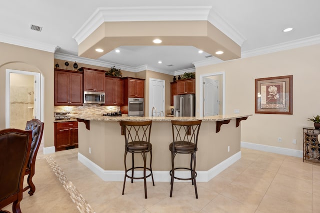 kitchen featuring light tile patterned floors, appliances with stainless steel finishes, a breakfast bar, a large island with sink, and ornamental molding