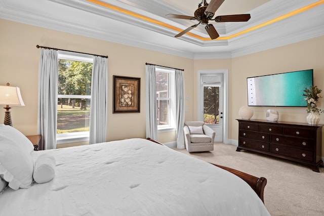 bedroom featuring light carpet, ornamental molding, a tray ceiling, and ceiling fan