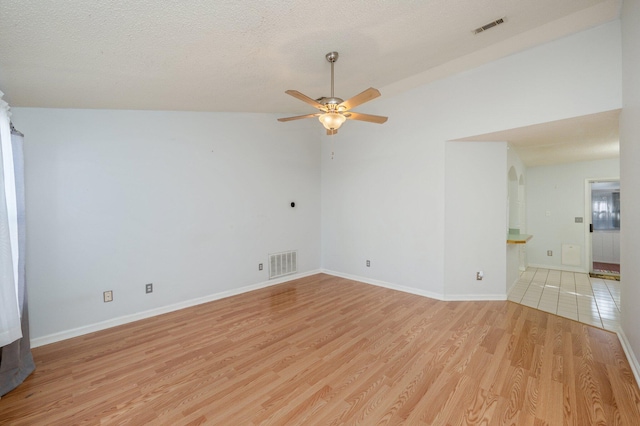 unfurnished room with light wood-type flooring, vaulted ceiling, ceiling fan, and a textured ceiling