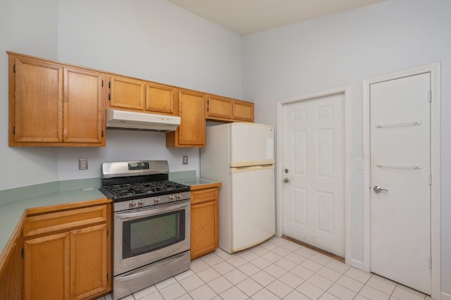 kitchen featuring gas stove, light tile patterned flooring, and white fridge