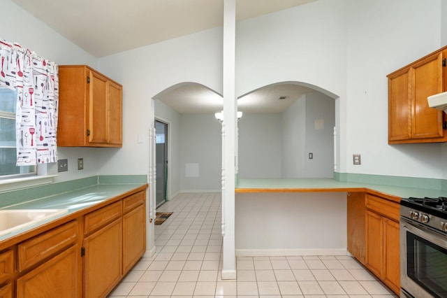 9 Holly Rd, Crestview, FL 32539 - kitchen featuring stainless steel range with gas stovetop, brown cabinetry, light tile patterned floors, and arched walkways