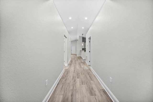 hallway with lofted ceiling and light wood-type flooring