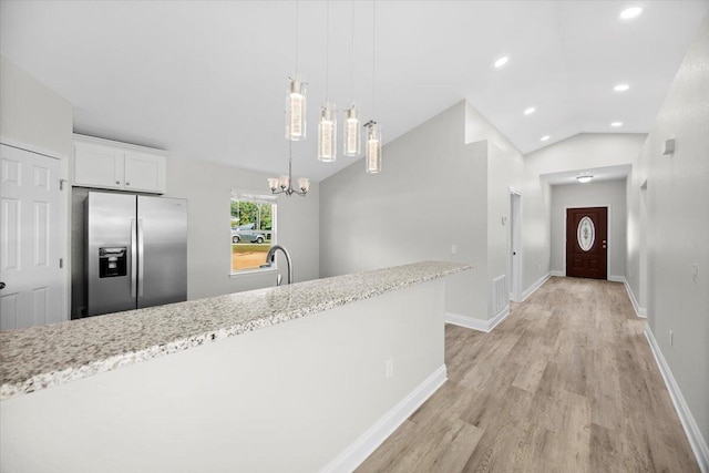 kitchen featuring lofted ceiling, stainless steel fridge with ice dispenser, white cabinetry, light stone countertops, and light wood-type flooring