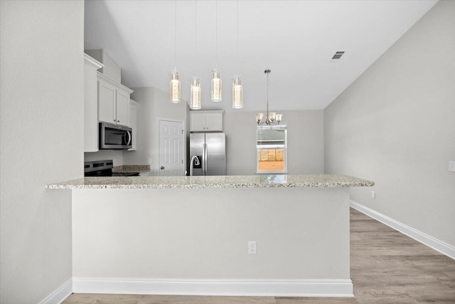 kitchen with appliances with stainless steel finishes, kitchen peninsula, white cabinetry, and light hardwood / wood-style floors