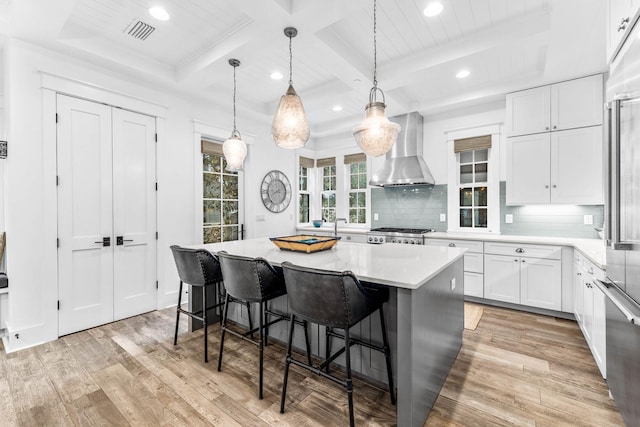 79 Cedar Post Rd, Santa Rosa Beach, FL 32459 - kitchen featuring wall chimney exhaust hood, a kitchen island, light hardwood / wood-style flooring, white cabinetry, and hanging light fixtures