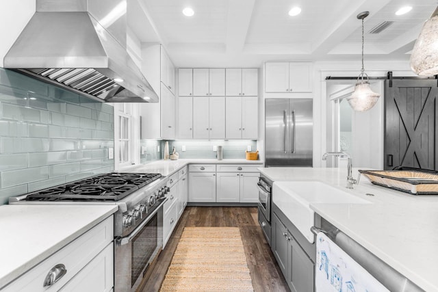 79 Cedar Post Rd, Santa Rosa Beach, FL 32459 - kitchen featuring white cabinetry, wall chimney exhaust hood, premium appliances, a barn door, and dark hardwood / wood-style flooring