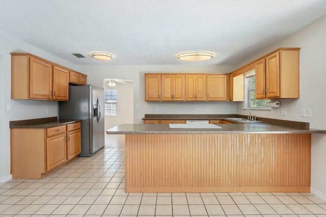 kitchen featuring kitchen peninsula, stainless steel fridge, ceiling fan, light tile patterned floors, and sink