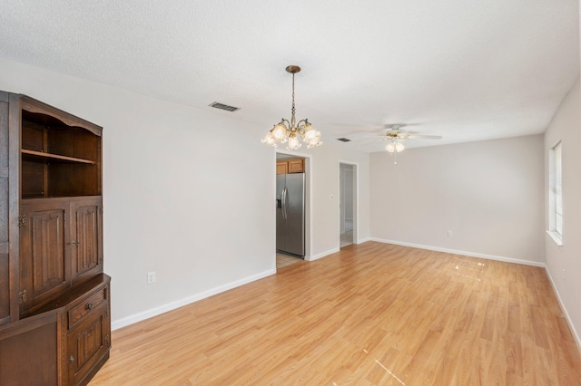 empty room featuring light hardwood / wood-style floors, a textured ceiling, and ceiling fan with notable chandelier