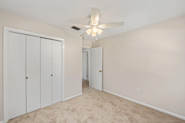 unfurnished bedroom with light carpet, a closet, a textured ceiling, and ceiling fan