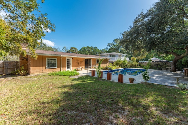 rear view of property with a yard, a patio area, and a fenced in pool