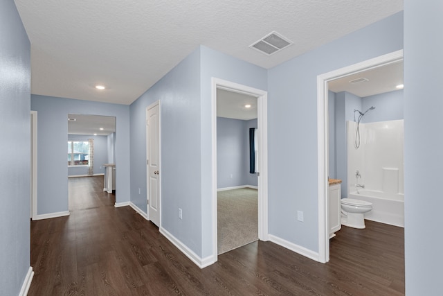 hall with dark wood-type flooring and a textured ceiling