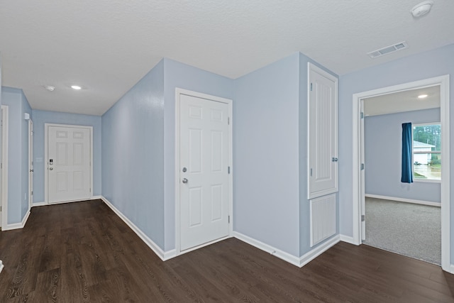 hall featuring dark wood-type flooring and a textured ceiling