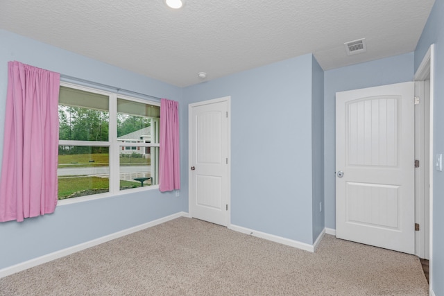 unfurnished bedroom featuring a closet, a textured ceiling, and light colored carpet