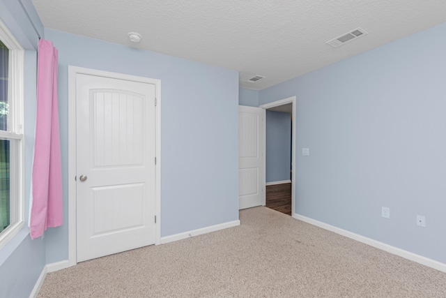 unfurnished bedroom with carpet floors and a textured ceiling