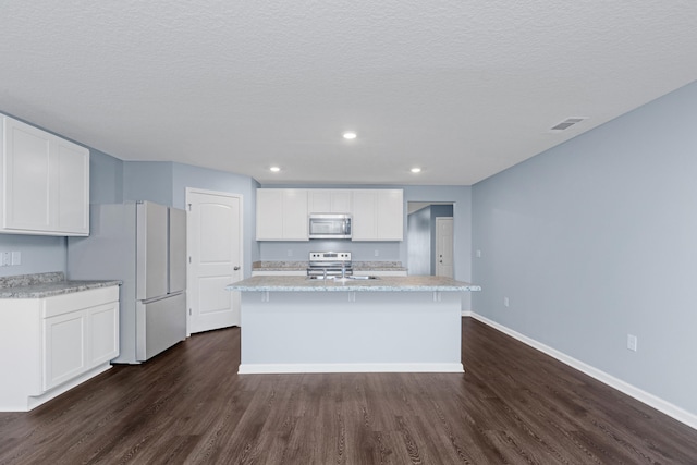 kitchen with white cabinetry, stainless steel appliances, dark hardwood / wood-style floors, and an island with sink