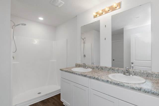 bathroom with hardwood / wood-style floors, vanity, a textured ceiling, and a shower