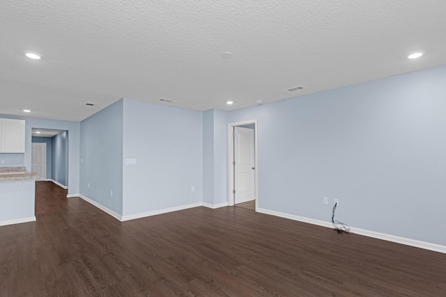 empty room with dark hardwood / wood-style flooring and a textured ceiling