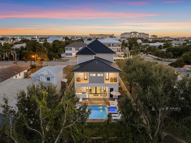 back house at dusk with a balcony and a patio