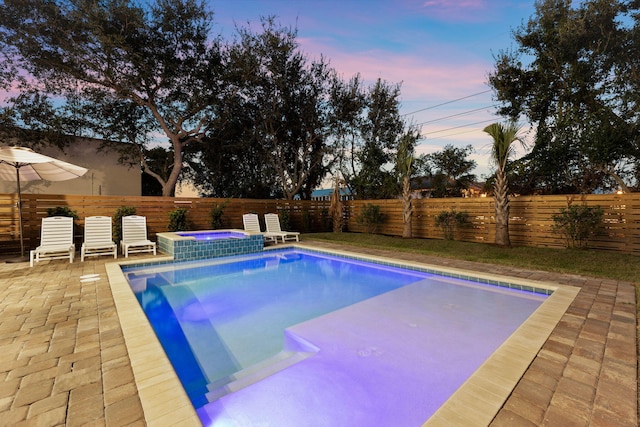 pool at dusk with an in ground hot tub