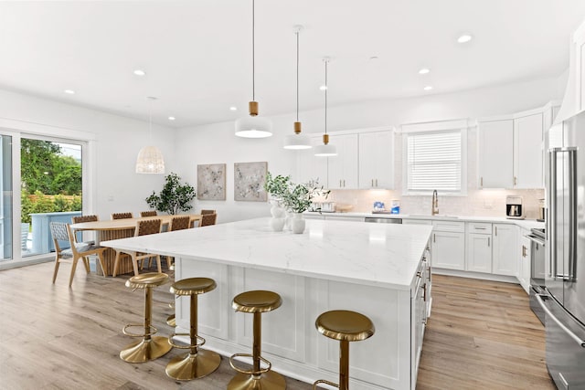 kitchen featuring white cabinetry, light hardwood / wood-style floors, decorative light fixtures, and a kitchen island