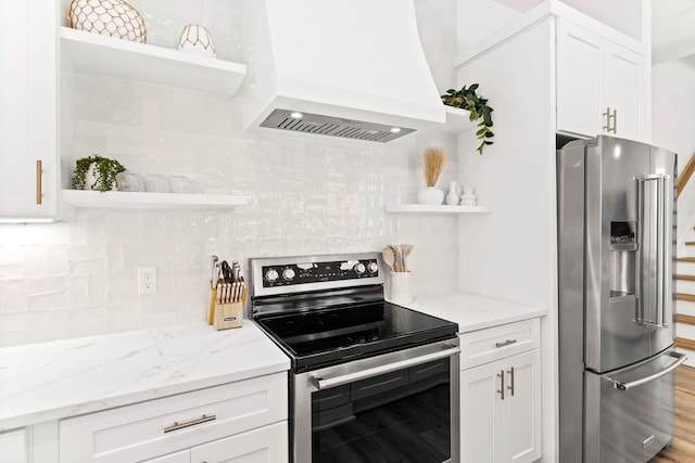 kitchen featuring white cabinets, decorative backsplash, light wood-type flooring, appliances with stainless steel finishes, and premium range hood