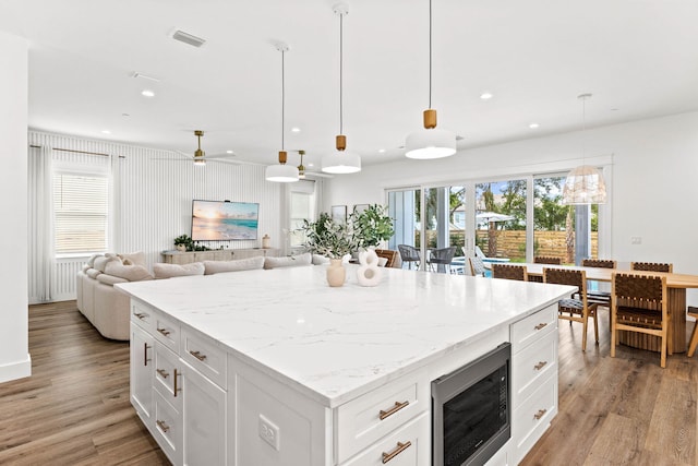 kitchen featuring white cabinets, hanging light fixtures, black microwave, and ceiling fan