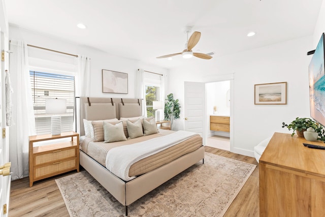 bedroom featuring light hardwood / wood-style flooring, ceiling fan, and ensuite bath