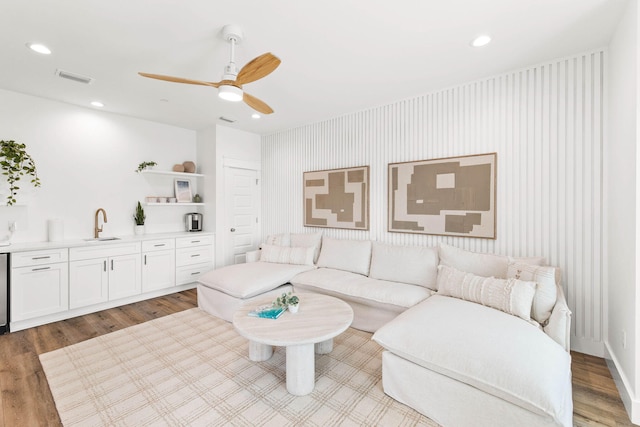 living room featuring hardwood / wood-style floors, ceiling fan, and sink