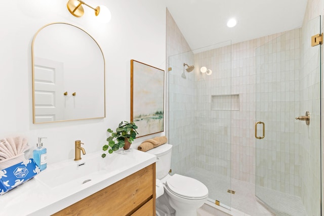 bathroom featuring toilet, vanity, and a shower with door