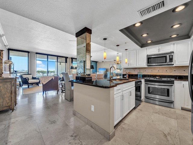 kitchen with a textured ceiling, white cabinetry, sink, pendant lighting, and stainless steel appliances