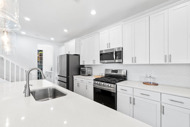 kitchen featuring pendant lighting, sink, tasteful backsplash, white cabinetry, and stainless steel appliances