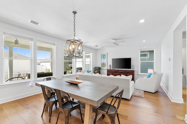 dining room with ceiling fan with notable chandelier and light wood-type flooring