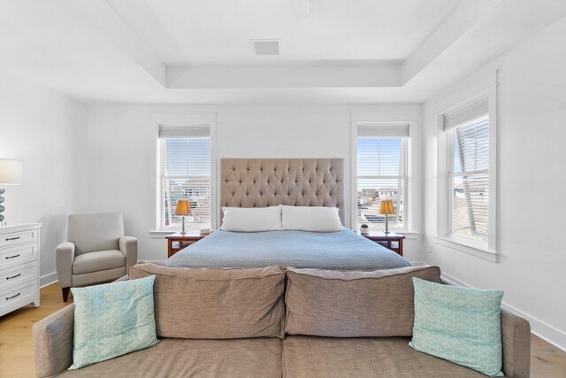 bedroom featuring a tray ceiling and light hardwood / wood-style flooring