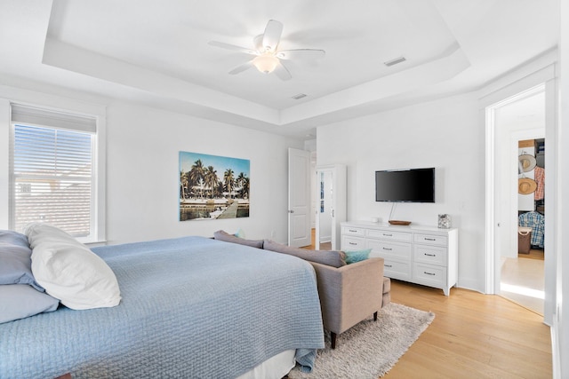 bedroom featuring a tray ceiling, ceiling fan, and light hardwood / wood-style floors