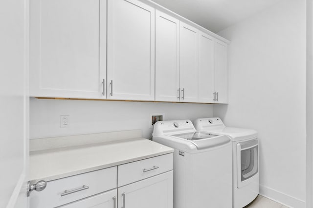 clothes washing area featuring cabinets, separate washer and dryer, and light tile patterned flooring