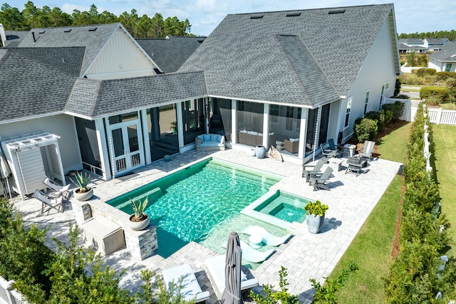 view of pool featuring an in ground hot tub, a patio area, a lawn, and a sunroom