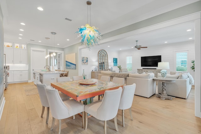 dining area featuring light hardwood / wood-style floors, crown molding, sink, and ceiling fan