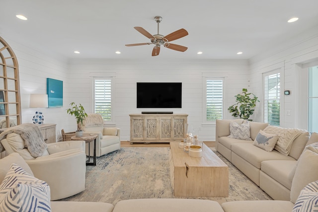 living room featuring a wealth of natural light, wooden walls, light hardwood / wood-style flooring, and ceiling fan