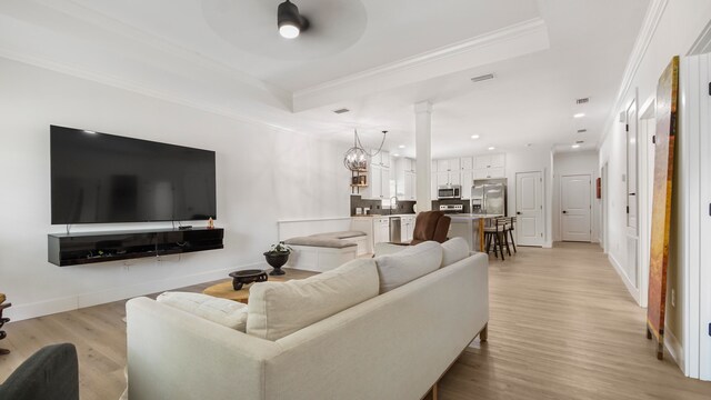 living room featuring ornamental molding, ceiling fan with notable chandelier, light hardwood / wood-style floors, and decorative columns