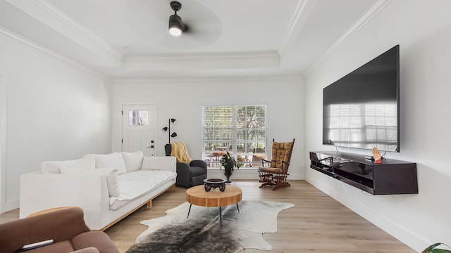 living room featuring crown molding, a raised ceiling, ceiling fan, and light hardwood / wood-style flooring