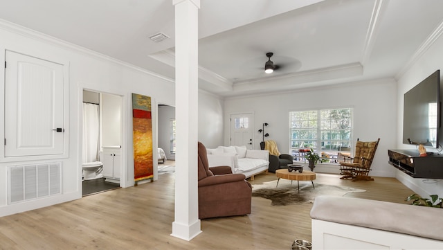 living room featuring ornate columns, a tray ceiling, and light hardwood / wood-style floors