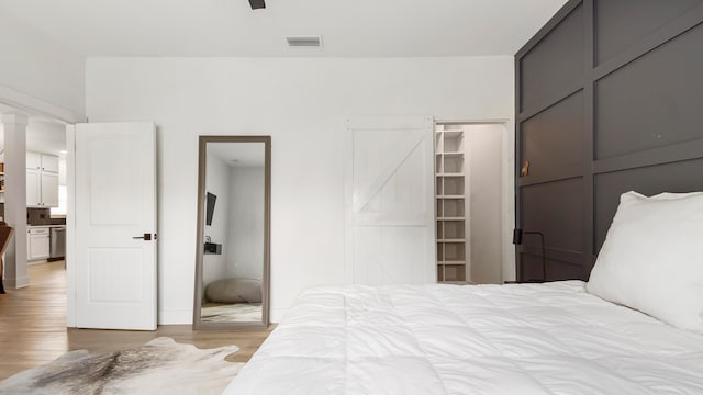 bedroom featuring a closet, a walk in closet, a barn door, and light hardwood / wood-style floors