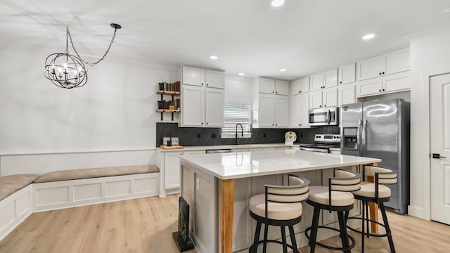 kitchen featuring a kitchen island, white cabinetry, pendant lighting, and stainless steel appliances