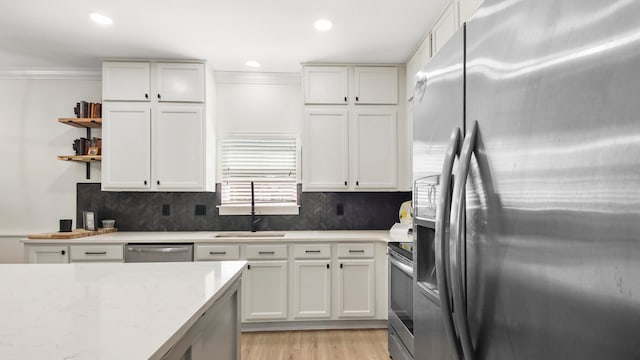 kitchen with stainless steel appliances, white cabinets, decorative backsplash, sink, and light hardwood / wood-style flooring